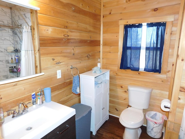 bathroom with a shower with curtain, toilet, wood finished floors, wooden walls, and vanity