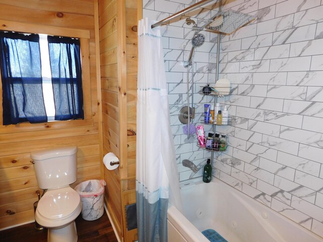 bathroom with wooden walls, shower / tub combo with curtain, and toilet