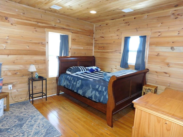 bedroom with light wood finished floors, wooden walls, and wood ceiling