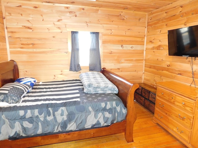 bedroom featuring wooden walls and light wood-style flooring