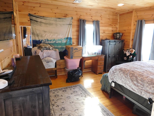 bedroom featuring visible vents, wood ceiling, light wood-style flooring, and wood walls