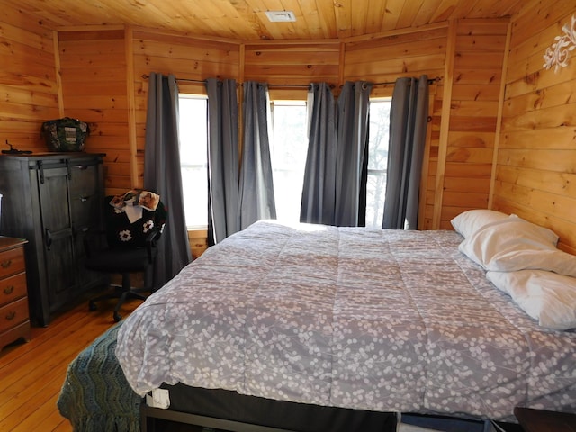 bedroom with wooden ceiling, wooden walls, and multiple windows