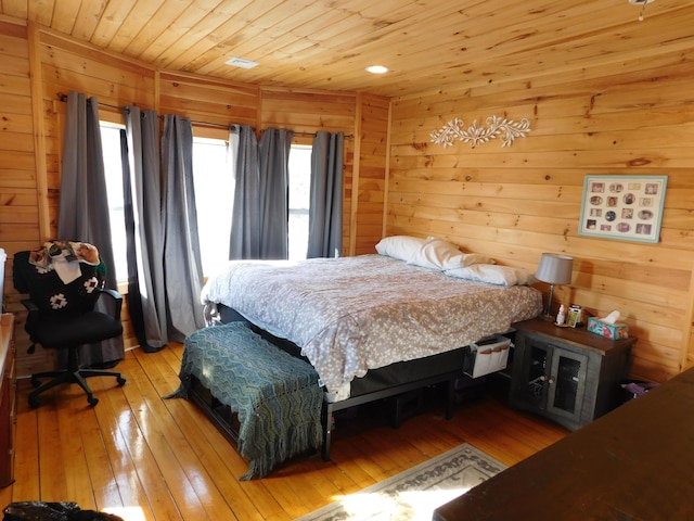 bedroom featuring wooden ceiling, wood walls, and light wood finished floors