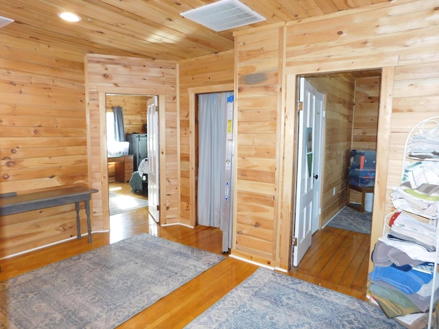 bedroom featuring hardwood / wood-style floors, wooden walls, wood ceiling, and visible vents