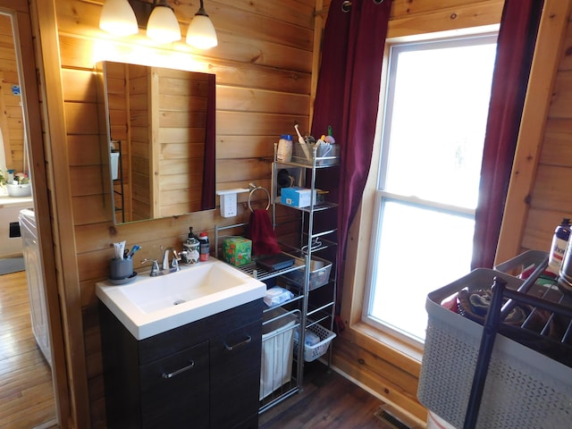 bathroom featuring vanity, wooden walls, wood finished floors, and visible vents