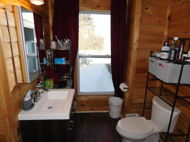 bathroom with vanity, wooden walls, toilet, and wood finished floors