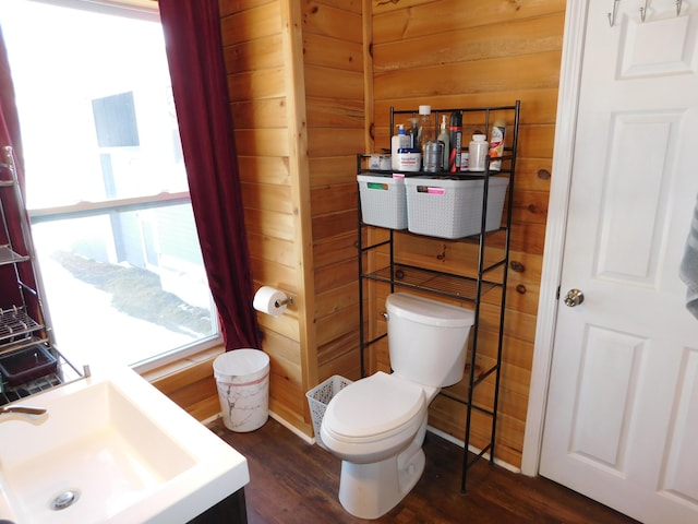 bathroom featuring a sink, wood finished floors, toilet, and wood walls