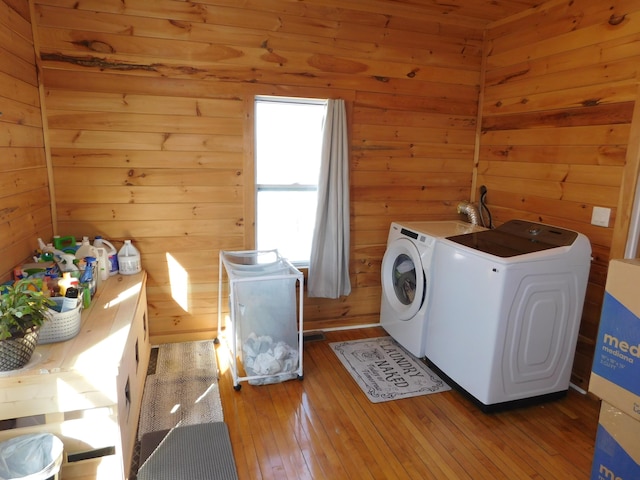 washroom featuring washer and dryer, wooden walls, hardwood / wood-style floors, and laundry area