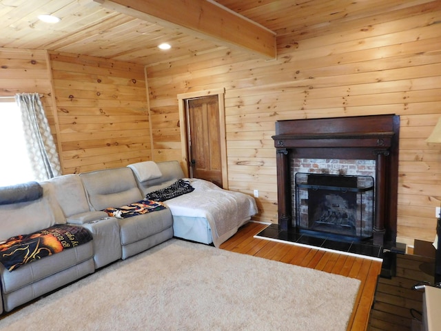 living area featuring beamed ceiling, a tile fireplace, wood ceiling, and hardwood / wood-style floors