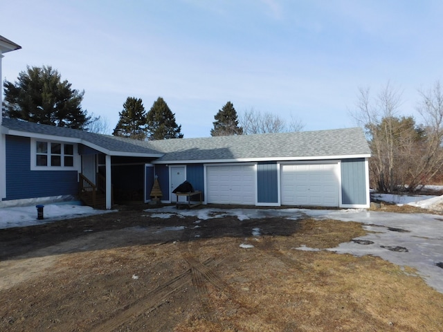 ranch-style home with entry steps, an attached garage, driveway, and roof with shingles