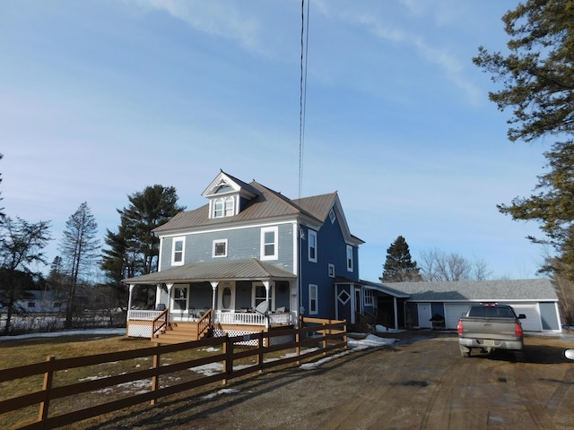 view of front facade featuring metal roof, a porch, a fenced front yard, and driveway