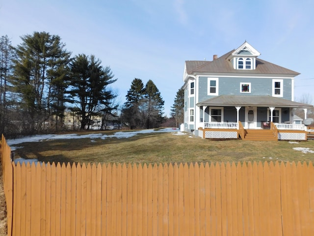 view of front of property featuring a front yard, fence, covered porch, and a chimney