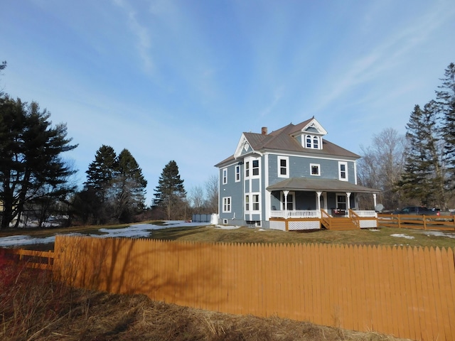 view of front facade featuring a fenced front yard, a porch, and a chimney