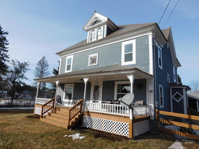 traditional style home featuring a front yard, covered porch, and metal roof