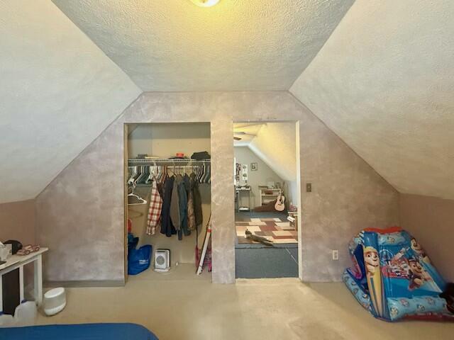 bonus room featuring lofted ceiling and a textured ceiling
