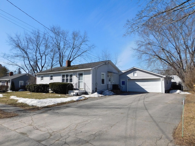 ranch-style home featuring driveway, a chimney, and an attached garage