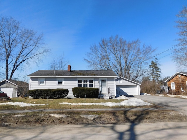 view of front facade with entry steps, an outbuilding, a garage, and a chimney