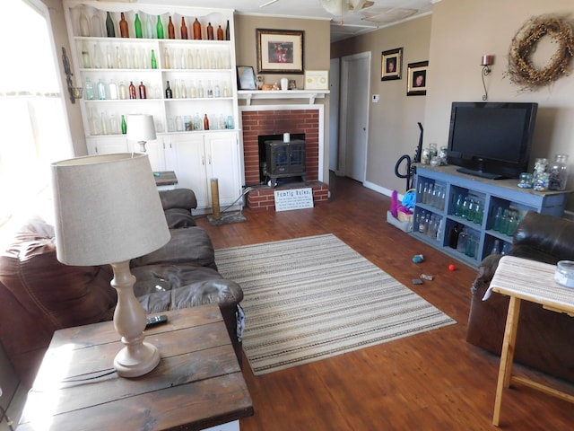 living area featuring a wood stove, wood finished floors, and baseboards