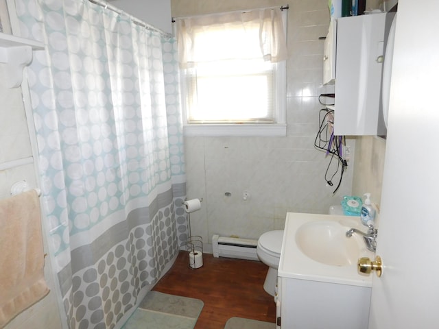 full bathroom featuring vanity, a shower with curtain, wood finished floors, a baseboard heating unit, and toilet