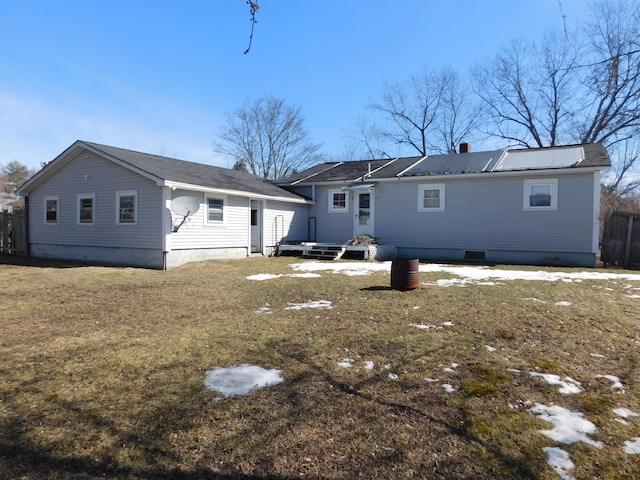 rear view of property with entry steps, a yard, and fence