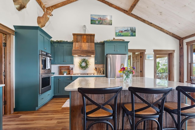 3062 Main St, Rangeley, ME 04970 - kitchen featuring appliances with stainless steel finishes, light wood-style flooring, light countertops, high vaulted ceiling, and a breakfast bar