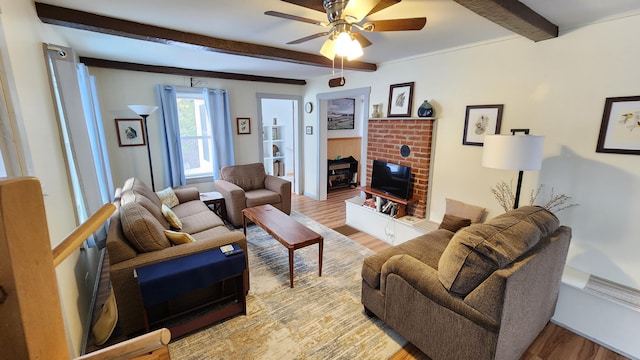 living room with beam ceiling, a fireplace, light wood finished floors, and ceiling fan