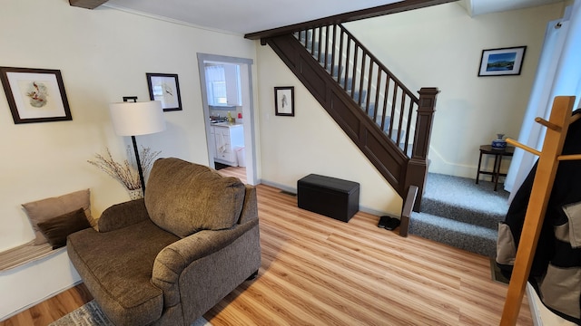 living area featuring baseboards, light wood-style floors, and stairs