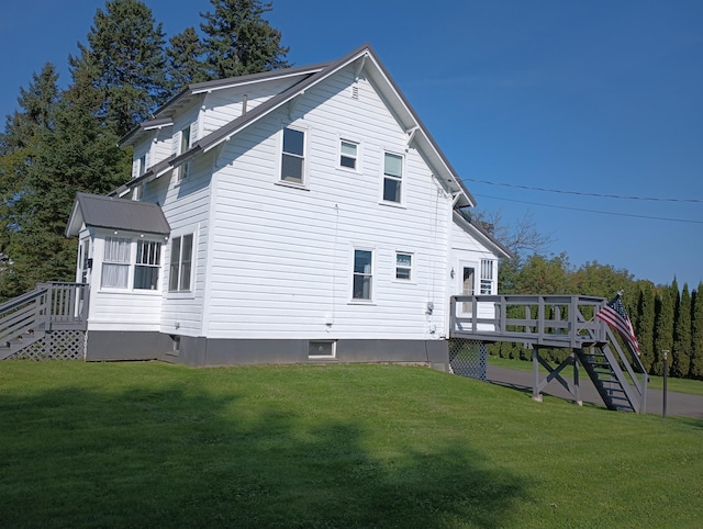 back of property with a wooden deck, a lawn, and stairway