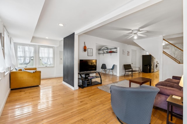 living room with baseboards, light wood-style floors, and a ceiling fan