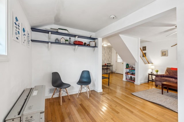 living area featuring lofted ceiling, light wood-style floors, visible vents, and baseboards