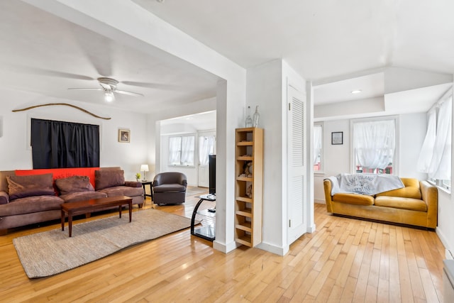 living room with baseboards, a ceiling fan, and wood-type flooring