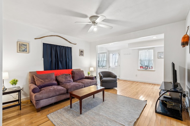 living area featuring baseboards, light wood-style floors, and a ceiling fan