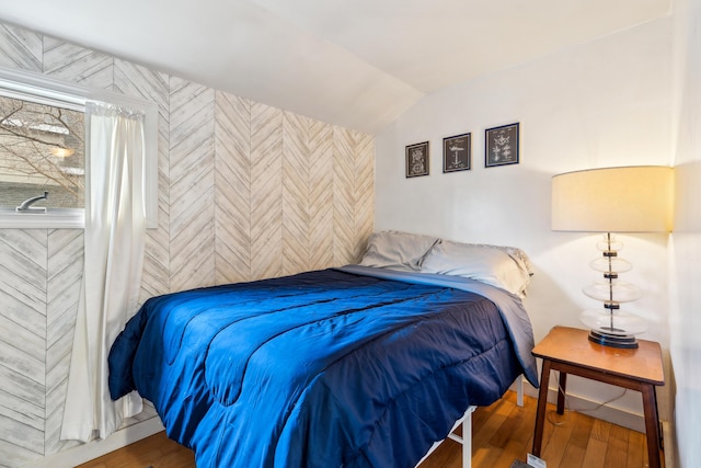 bedroom with wood finished floors and vaulted ceiling