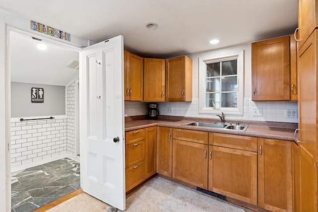 kitchen with a sink, tasteful backsplash, recessed lighting, and brown cabinetry