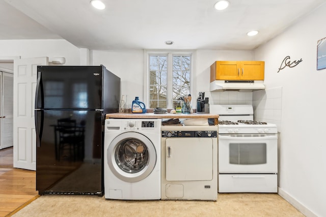 kitchen featuring washer / dryer, white gas range oven, freestanding refrigerator, and under cabinet range hood