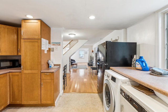 kitchen with brown cabinets, black appliances, washer / clothes dryer, and light countertops