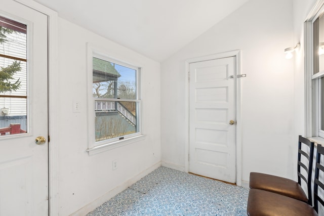 doorway with plenty of natural light, baseboards, and vaulted ceiling