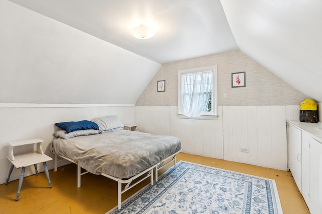 bedroom with lofted ceiling and wainscoting