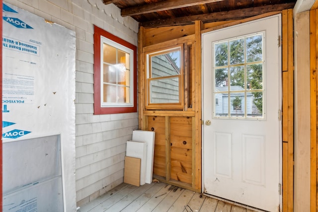 entryway with beam ceiling, wooden walls, light wood-style flooring, and wooden ceiling