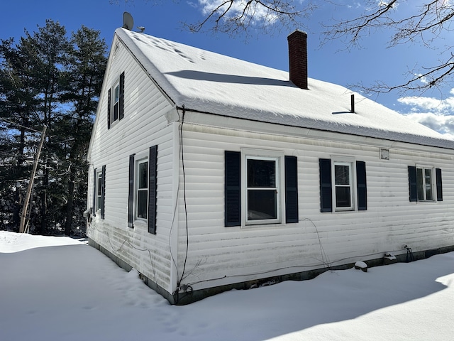 view of snowy exterior with a chimney