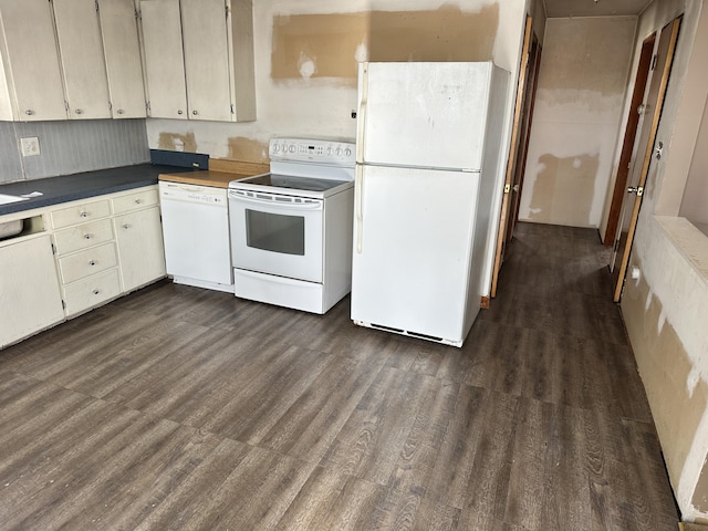 kitchen with dark countertops, white appliances, and dark wood-style flooring