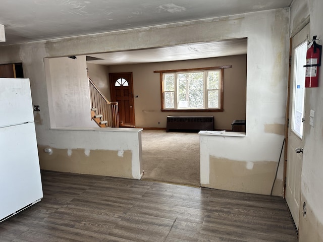 entrance foyer with stairs, wood finished floors, and radiator heating unit