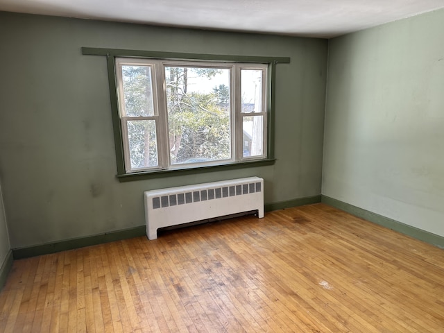 unfurnished room featuring radiator, baseboards, and wood-type flooring