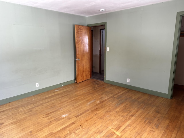 unfurnished room with hardwood / wood-style floors and baseboards