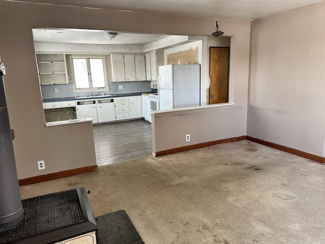 kitchen with tasteful backsplash, baseboards, dark carpet, white appliances, and a sink