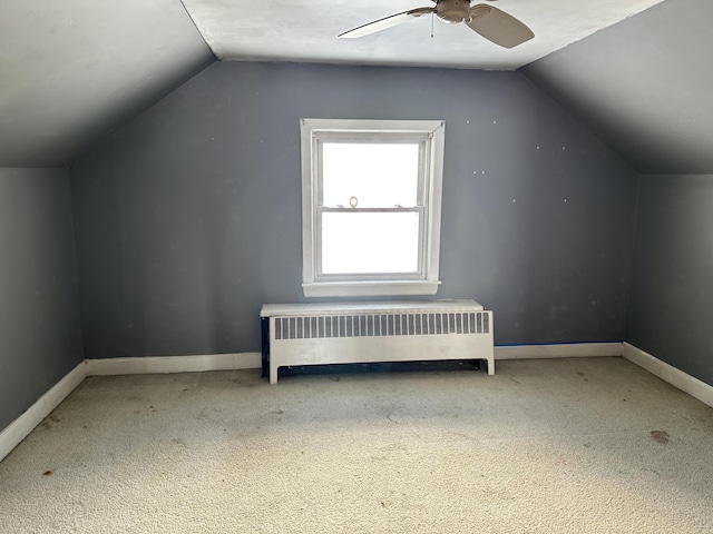 additional living space with lofted ceiling, a ceiling fan, radiator heating unit, carpet flooring, and baseboards