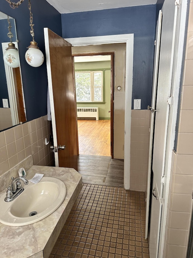 bathroom with tile patterned flooring, tile walls, radiator, and a sink