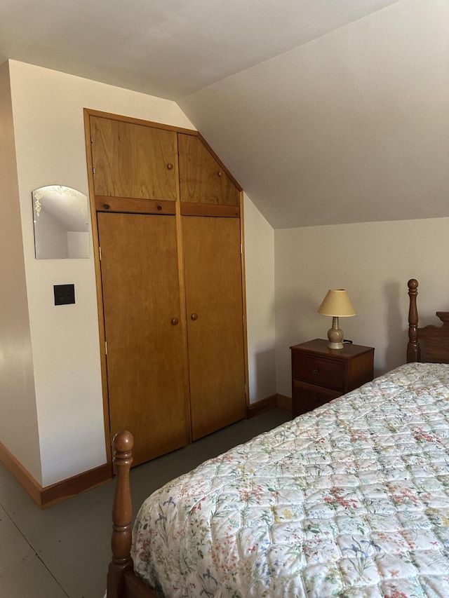 bedroom with a closet, baseboards, and vaulted ceiling