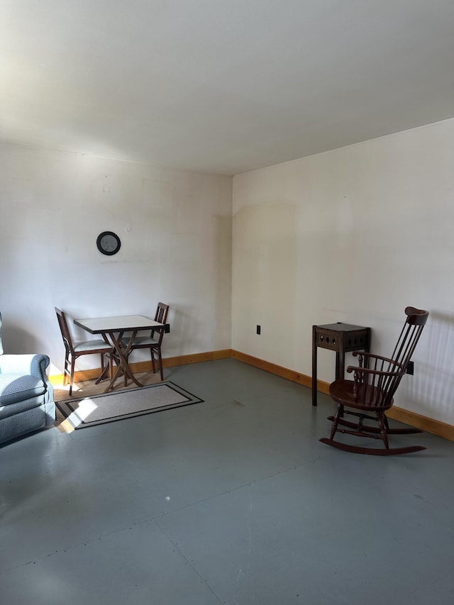 living area featuring baseboards and concrete flooring