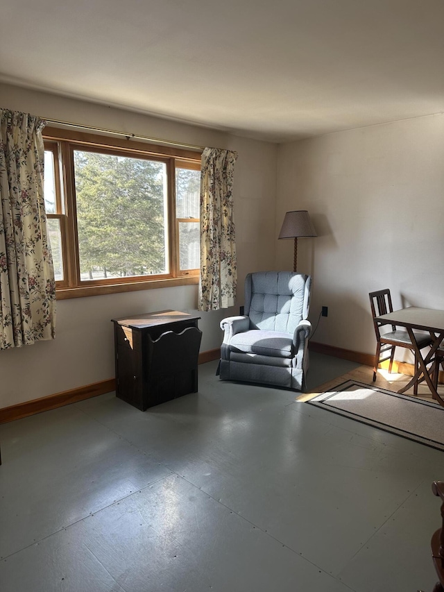 sitting room featuring concrete floors and baseboards